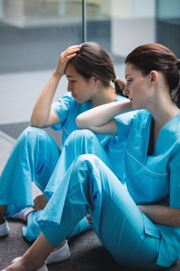 Enfermeiras tristes sentadas no corredor _ Foto Grátis